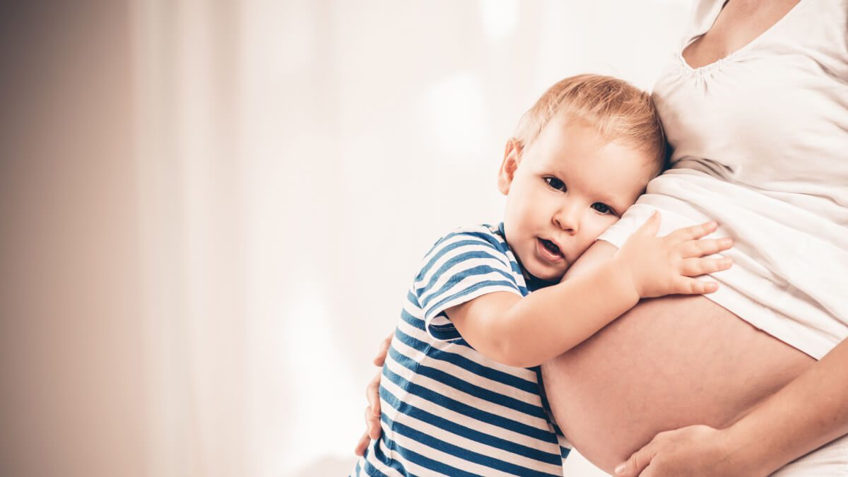 toddler cuddling mother's pregnant stomach