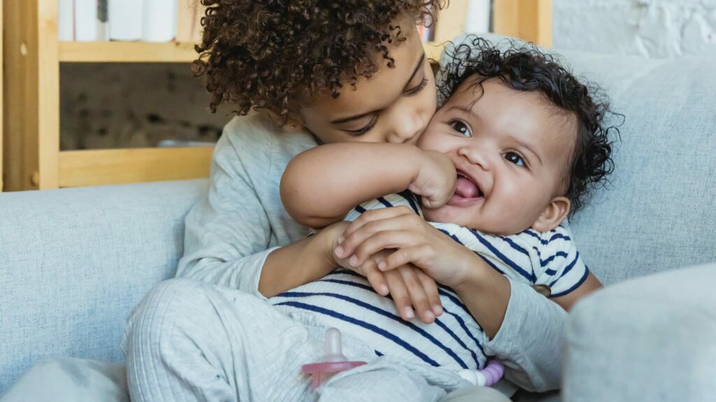 toddler and new baby brother hugging