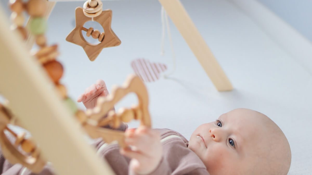 baby playing under play gym