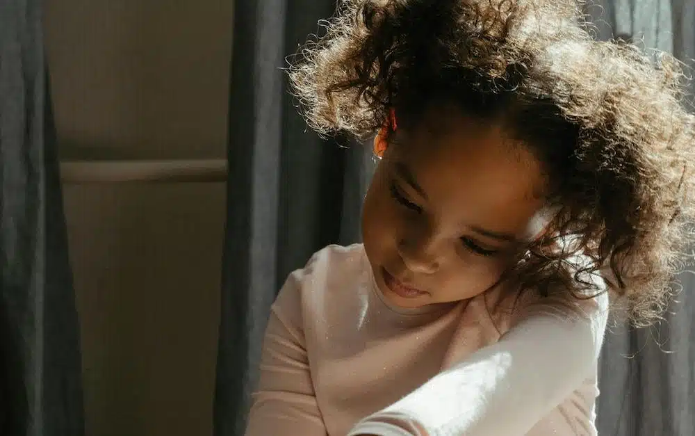 Girl with curly hair looking down.