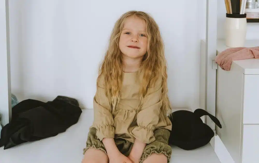 Smiling girl in beige outfit.